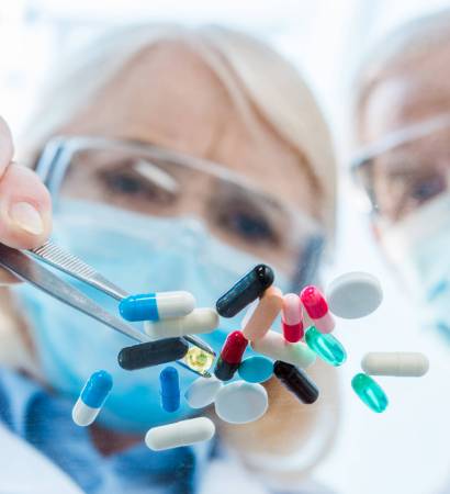 Close-up view of scientists in protective workwear working with various pills
